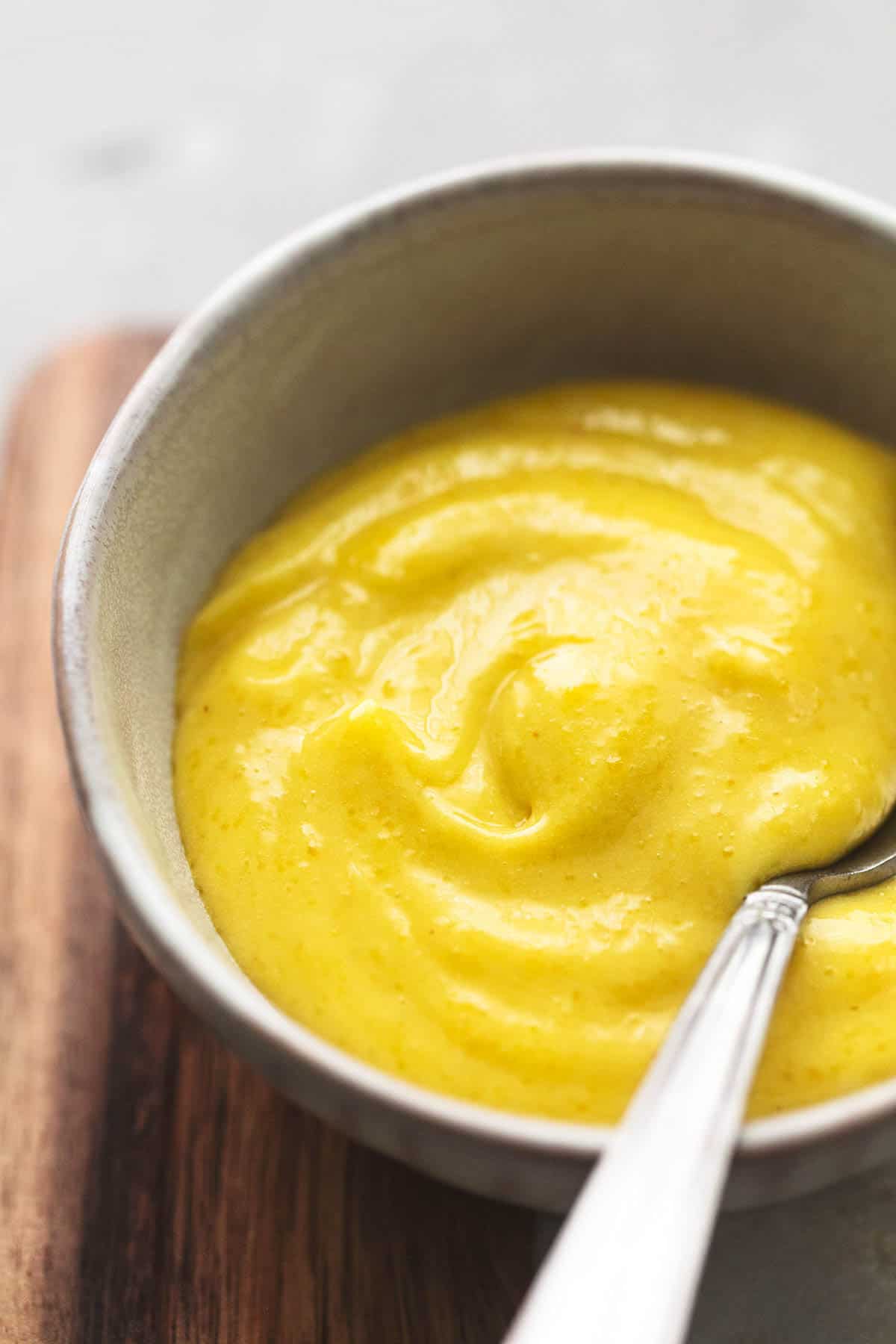 close up of garlic aioli in a small bowl with a spoon.