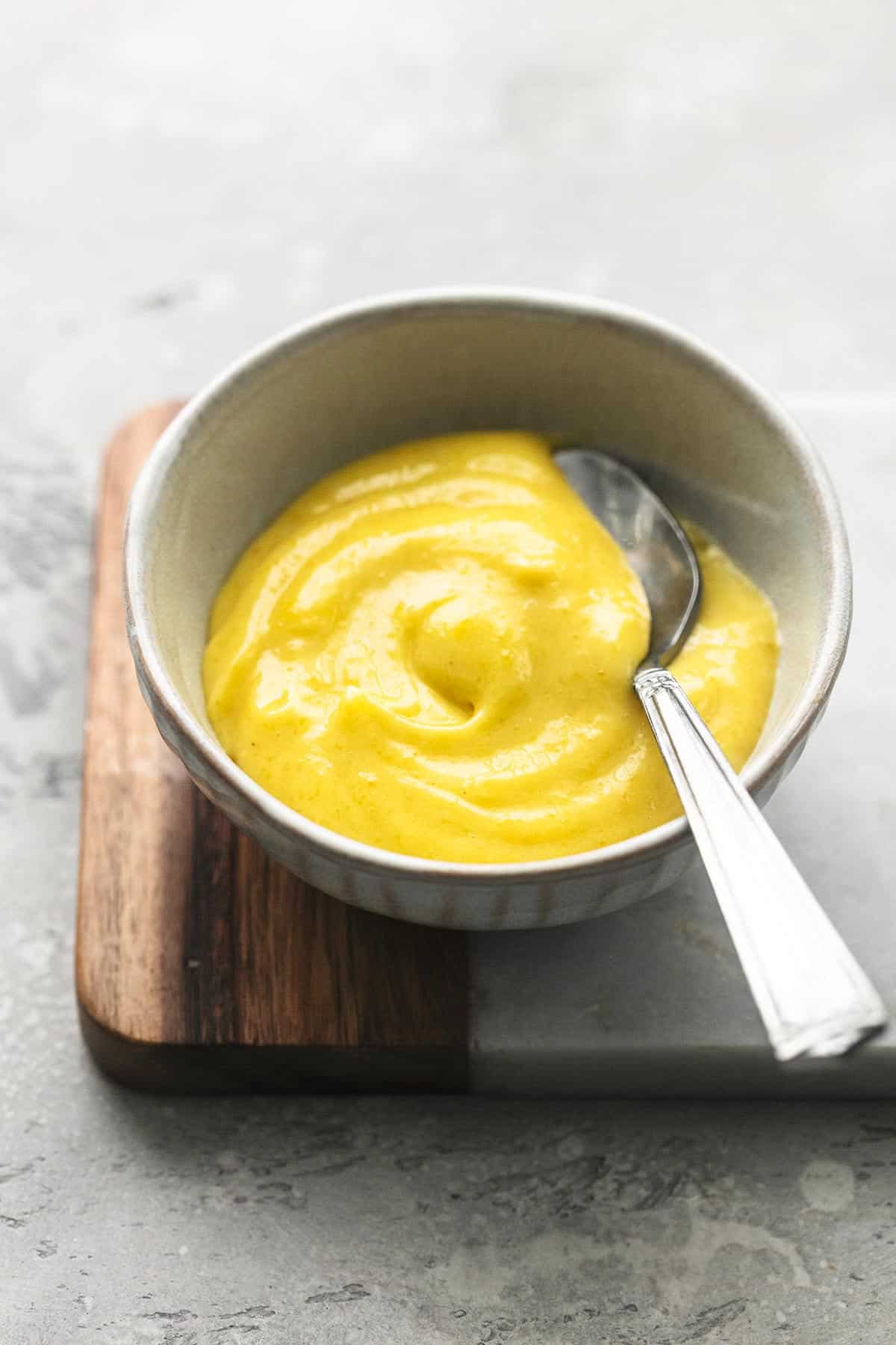 garlic aioli in a small bowl with a spoon on top of a cutting board.