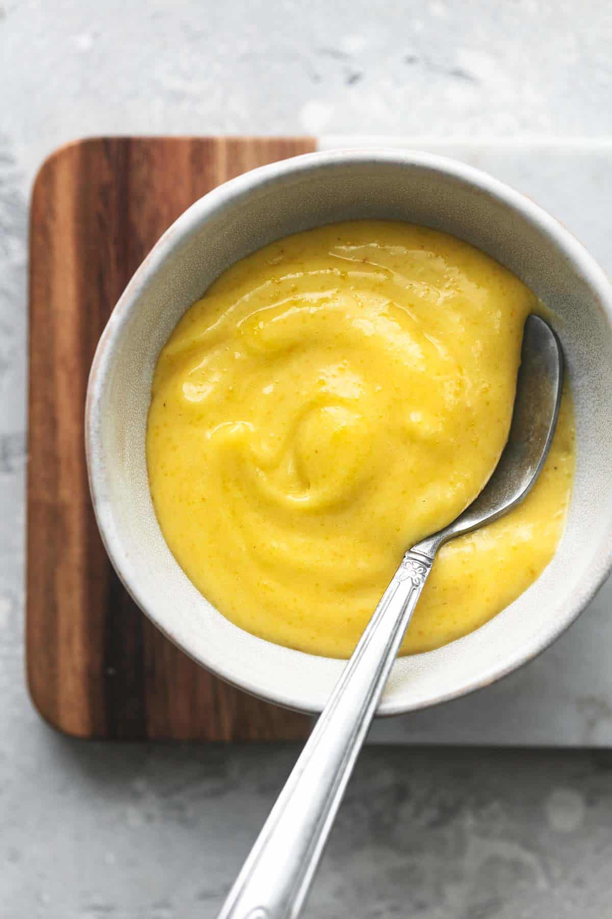 top view of garlic aioli in a small bowl with a spoon on top of cutting board.