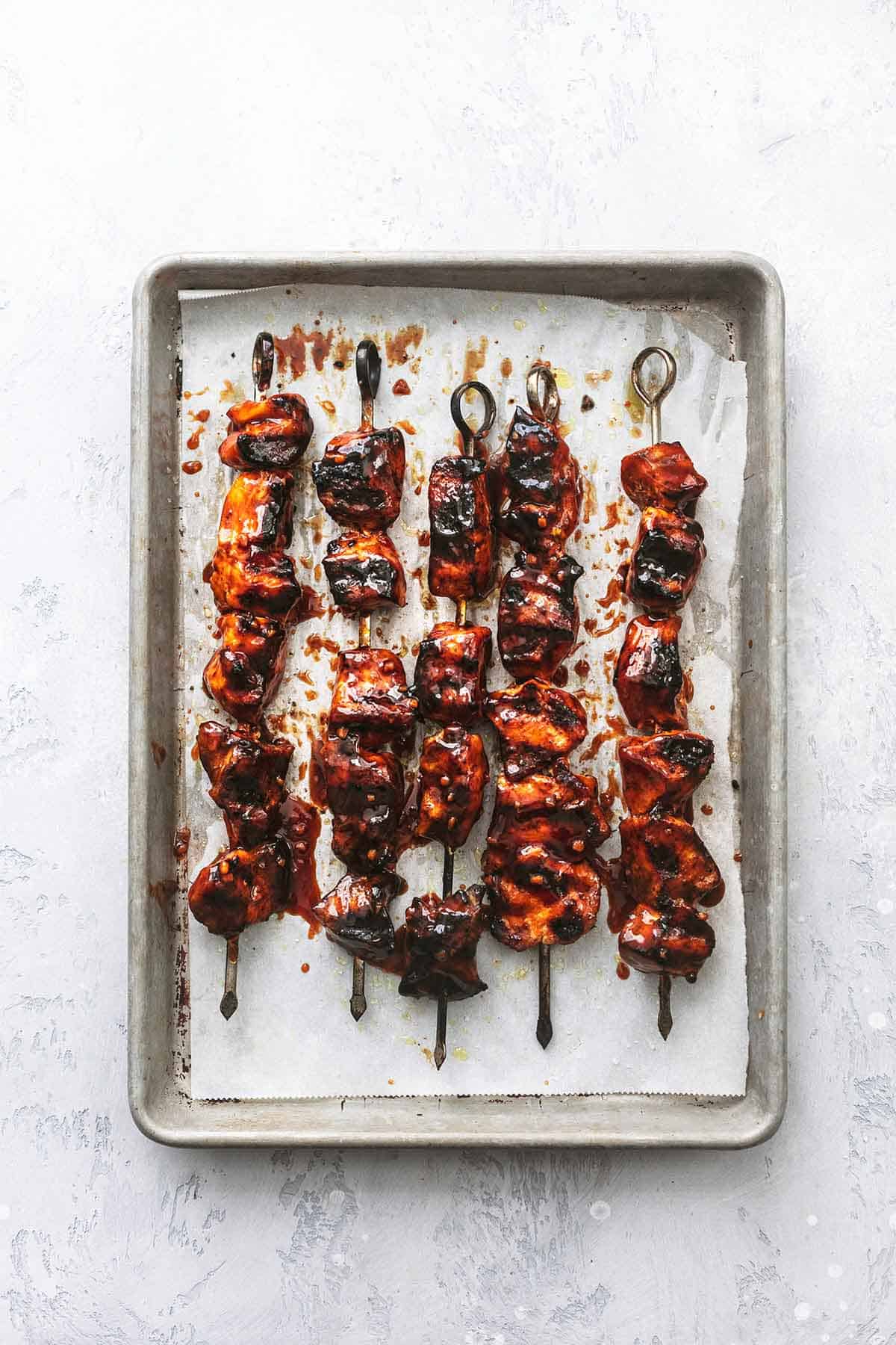 top view of Korean bbq chicken on skewers on a baking sheet.