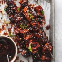 overhead view of chicken on skewers on sheet pan with bowl of sauce