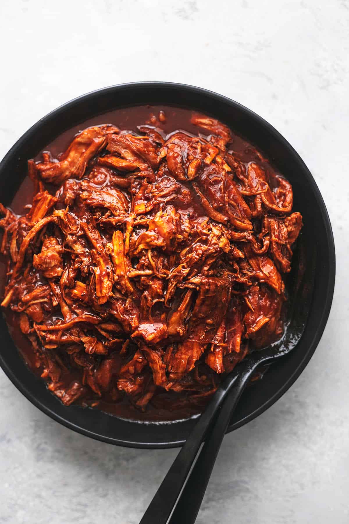 top view of pulled pork with forks on a plate.