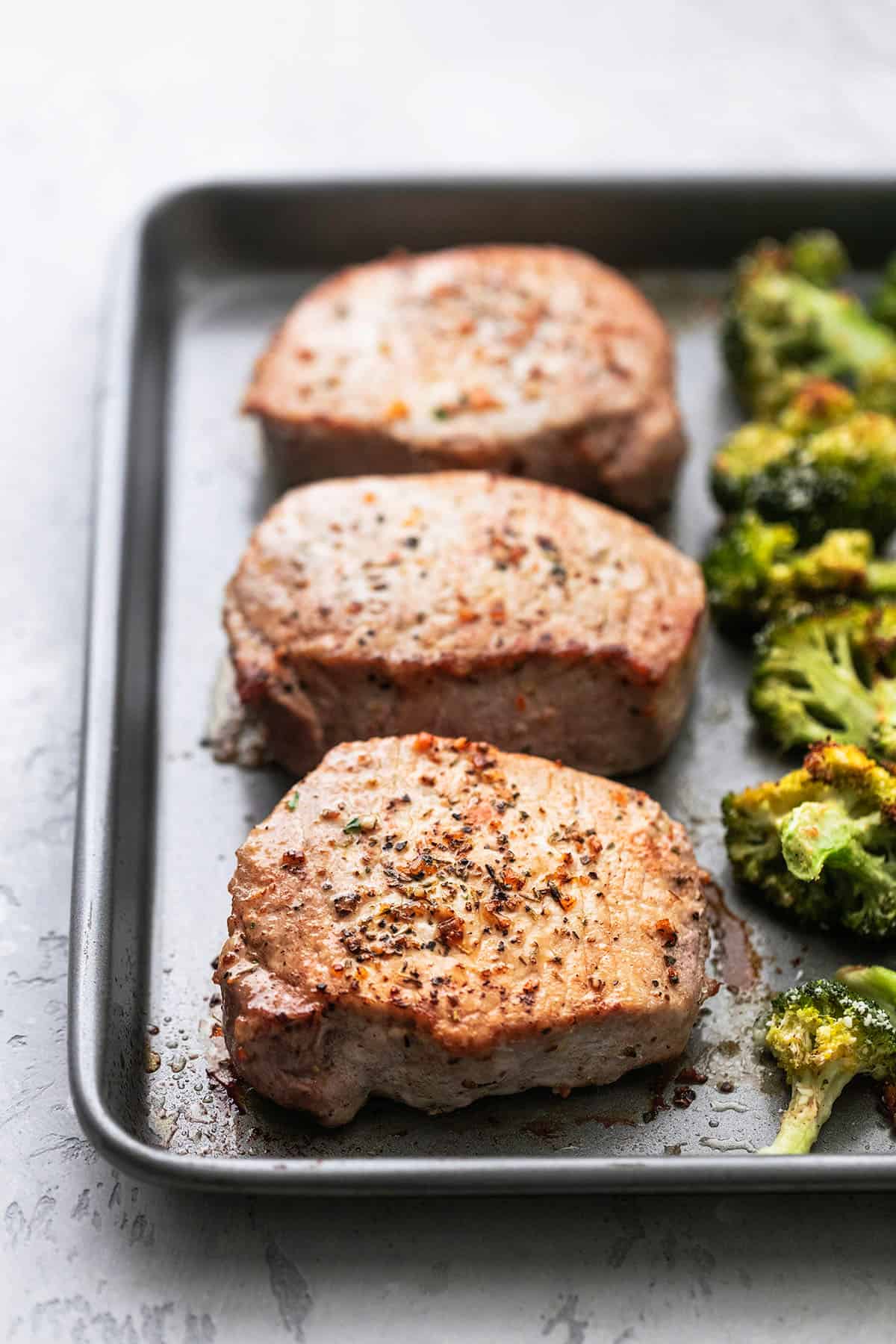 three cooked pork chops on a sheet pan