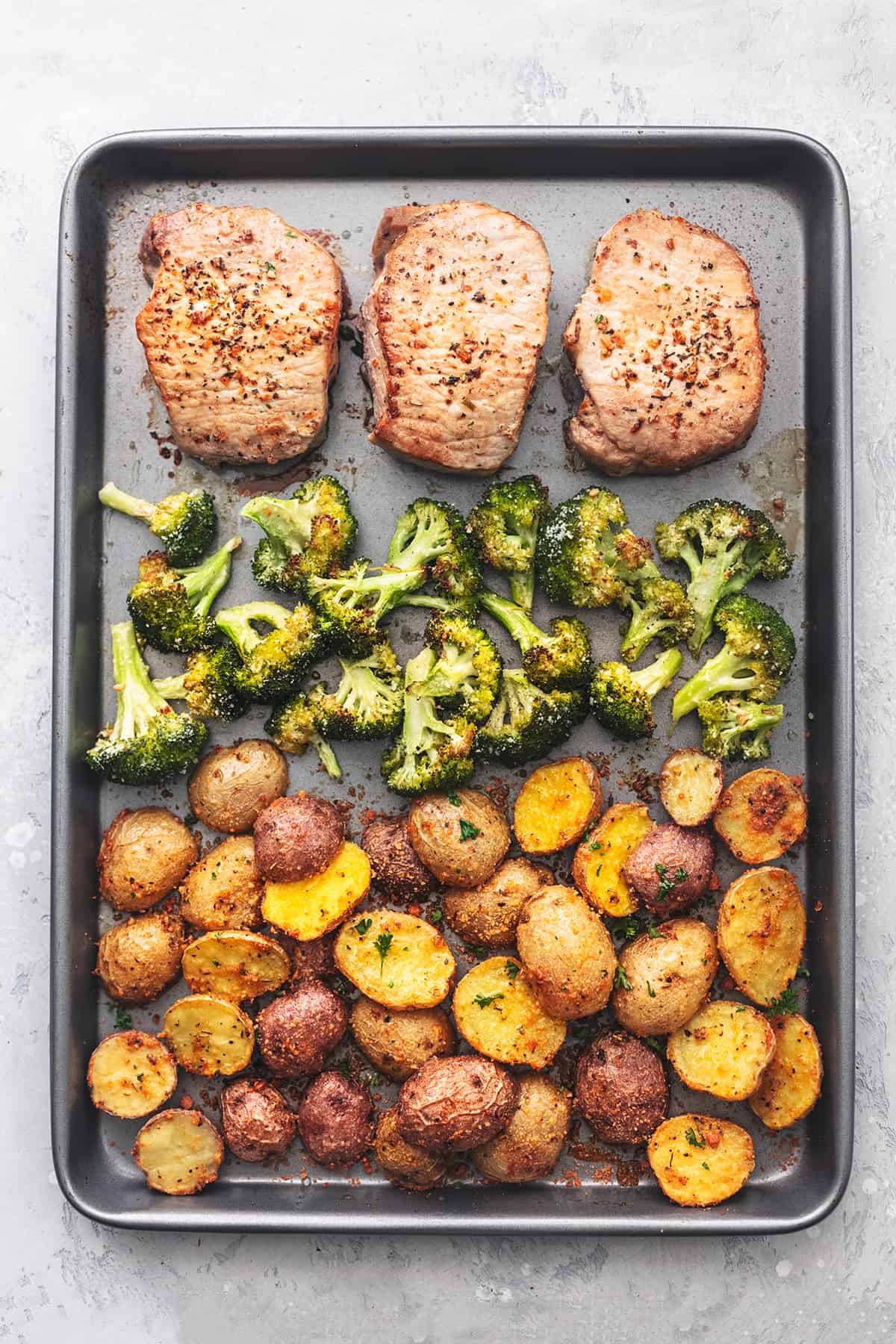 overhead view of sheet pan meal with pork chops, broccoli, and potatoes