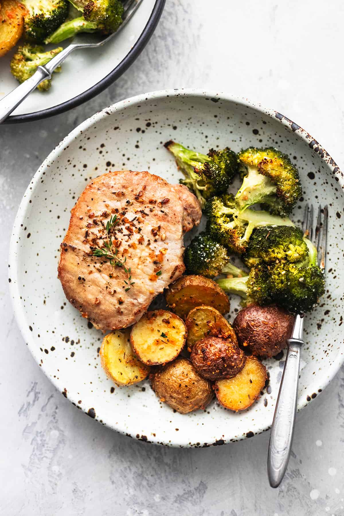 overhead view of a dish with pork chops, broccoli, and potatoes