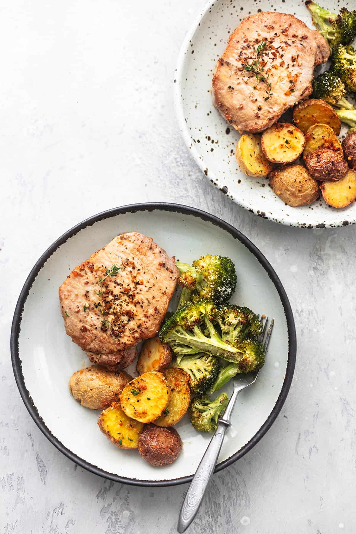 overhead view of two plates with pork chops and vegetables