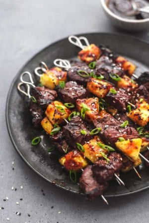 steak skewers with pineapple on a black plate