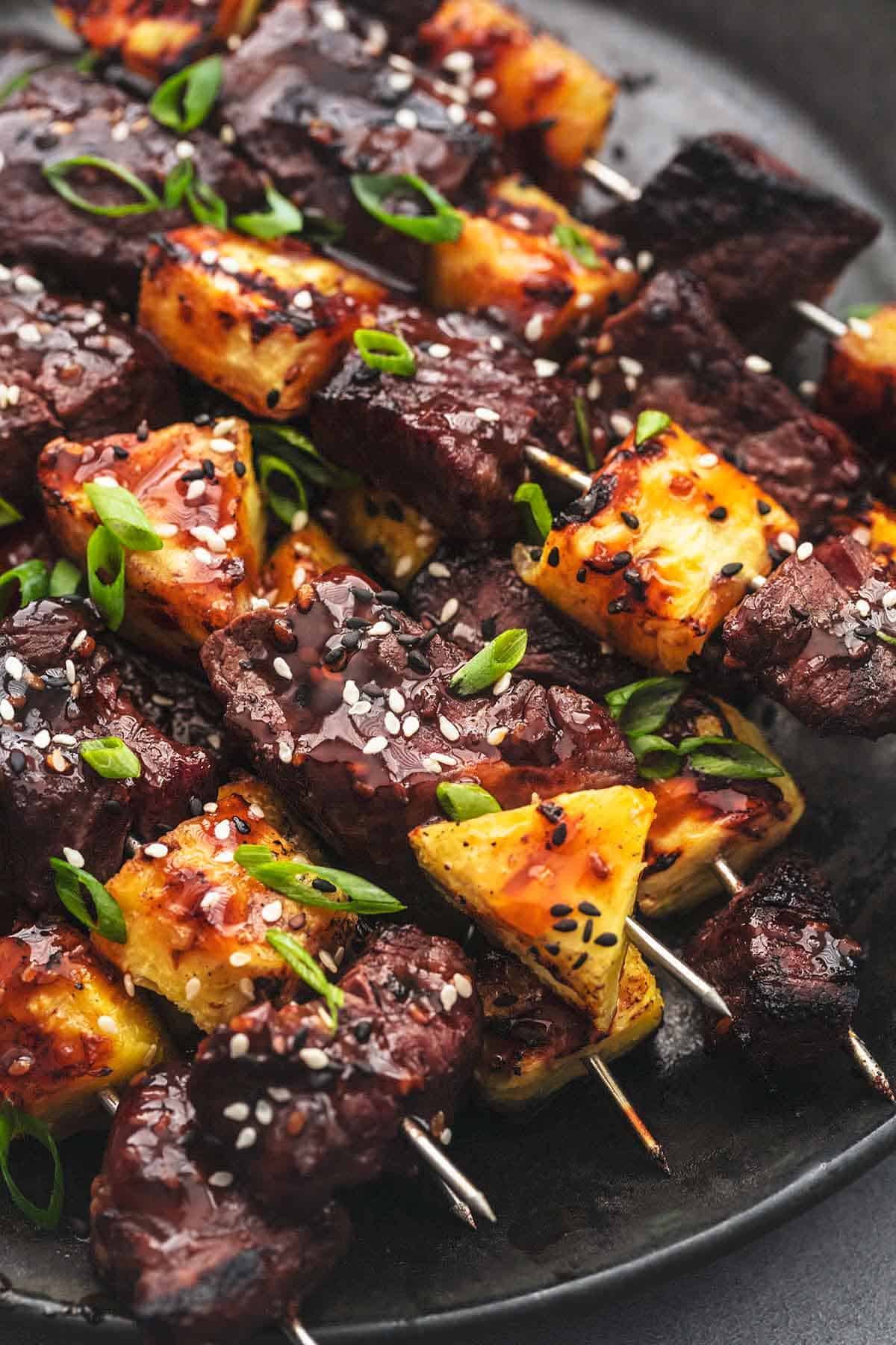close up of teriyaki steak and pineapple kabobs on a plate.