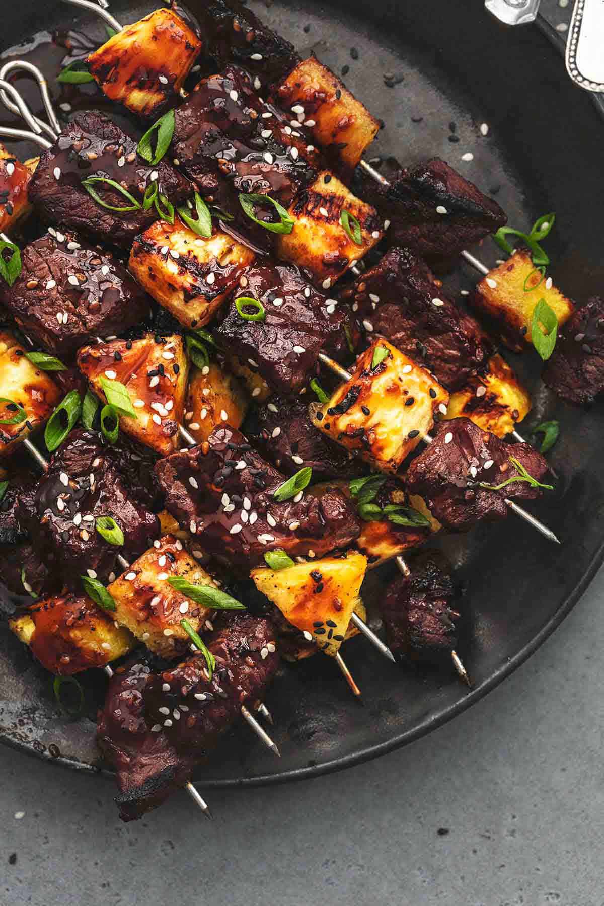 close up top view of teriyaki steak and pineapple kabobs on a plate.