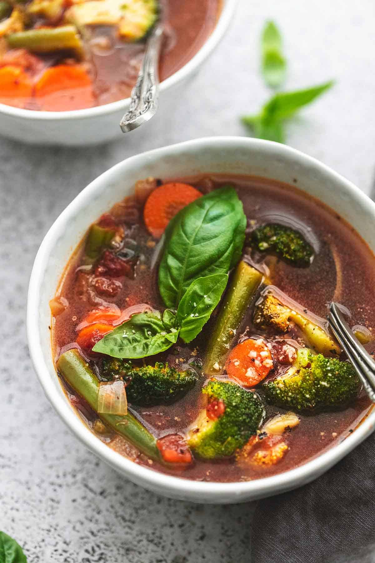 close up of vegetable soup with a spoon in a bowl.