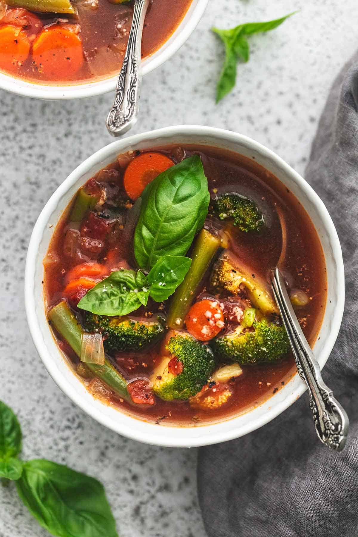 top view of vegetable soup with a spoon in a bowl.