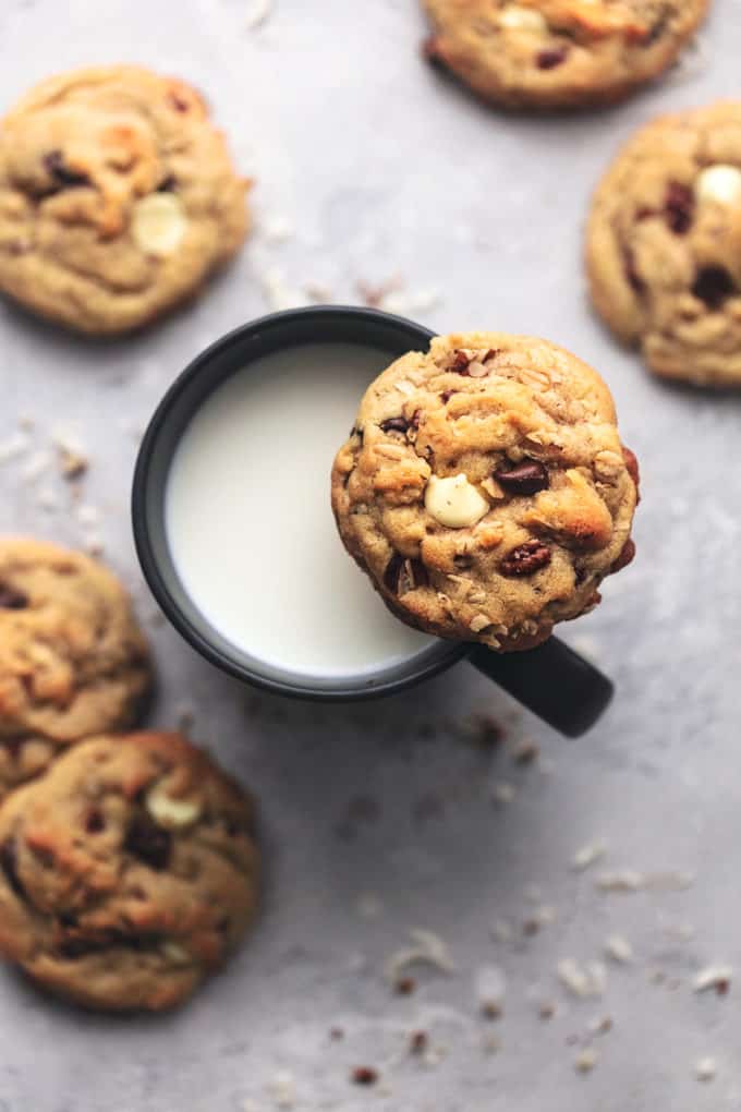 cookie on the side of a cup of milk surround by more cookies