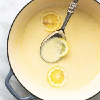 overhead view of butter sauce in skillet with serving spoon and lemon slices