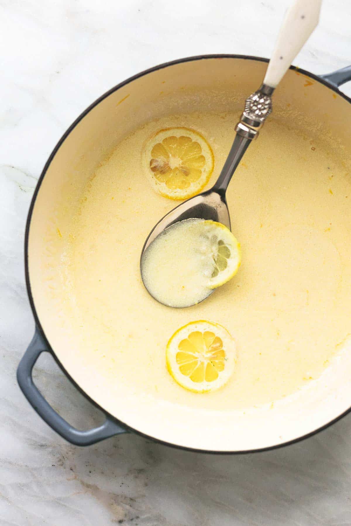 overhead view of butter sauce in skillet with serving spoon and lemon slices