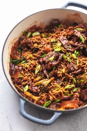 45 degree angle of skillet filled with beef, broccoli and noodles topped with green onions