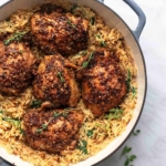 overhead three quarter view of baked chicken and orzo with herbs in a pan
