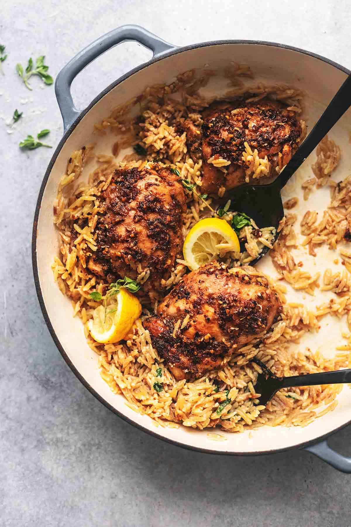 top view of Green chicken and orzo with serving spoons in a skillet.