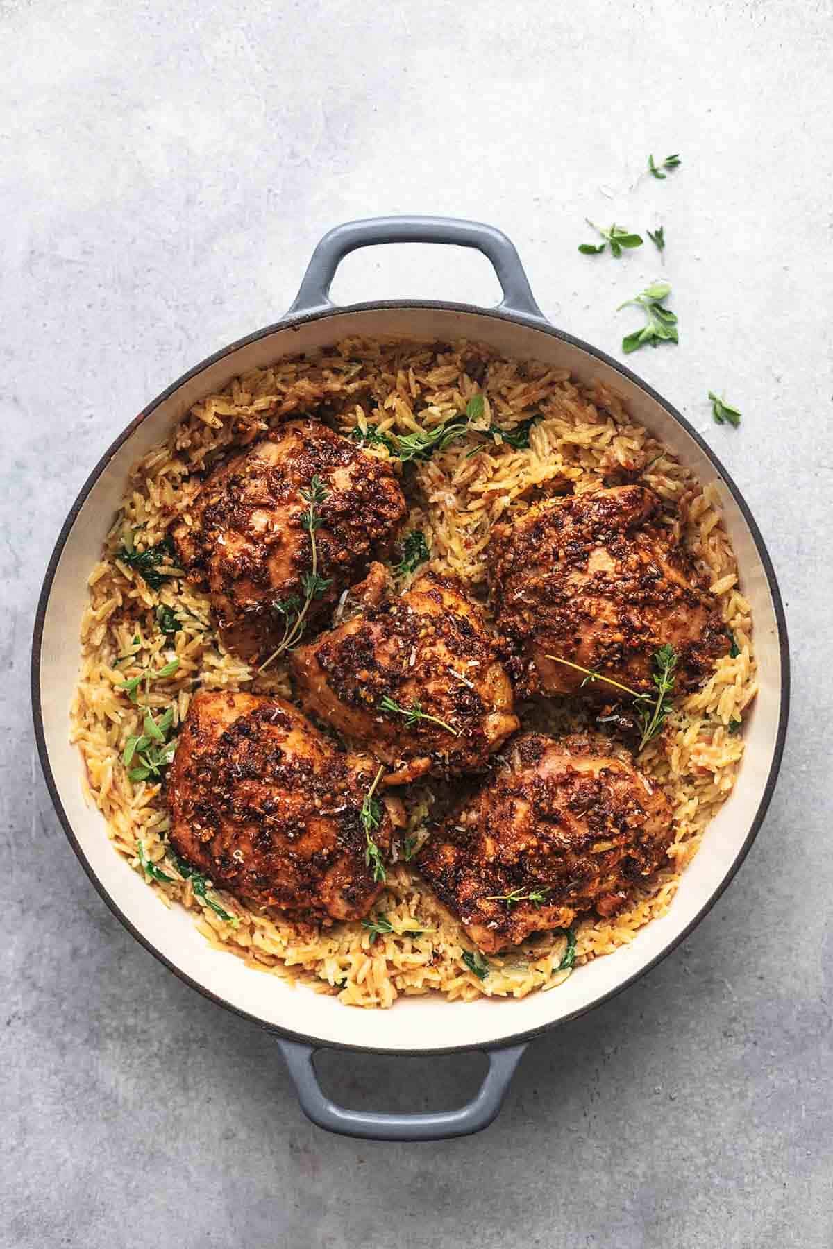 overhead view of one pot Greek chicken with herbs and creamy orzo in a pan