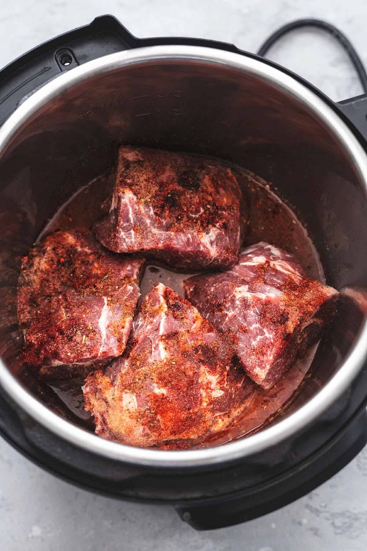 top view of large chunks of uncooked pork in liquid in an instant pot.