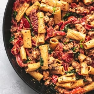 1/3 of a a black skillet filled with creamy pasta with red peppers and fresh thyme on top