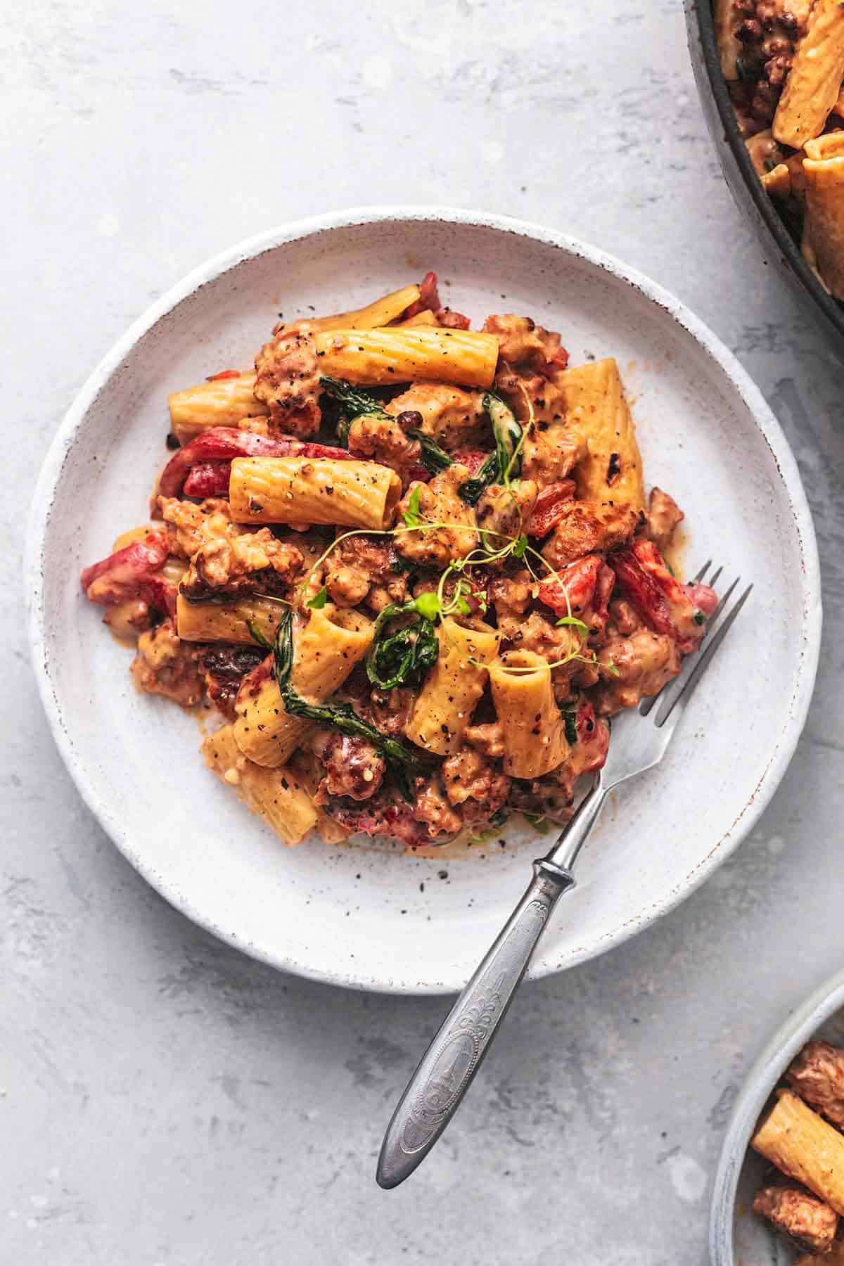 top view of tuscan sausage pasta with a fork on a plate.