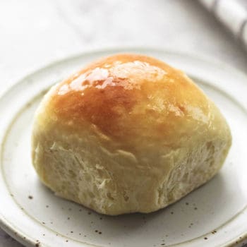 up close single baked dinner roll on a plate