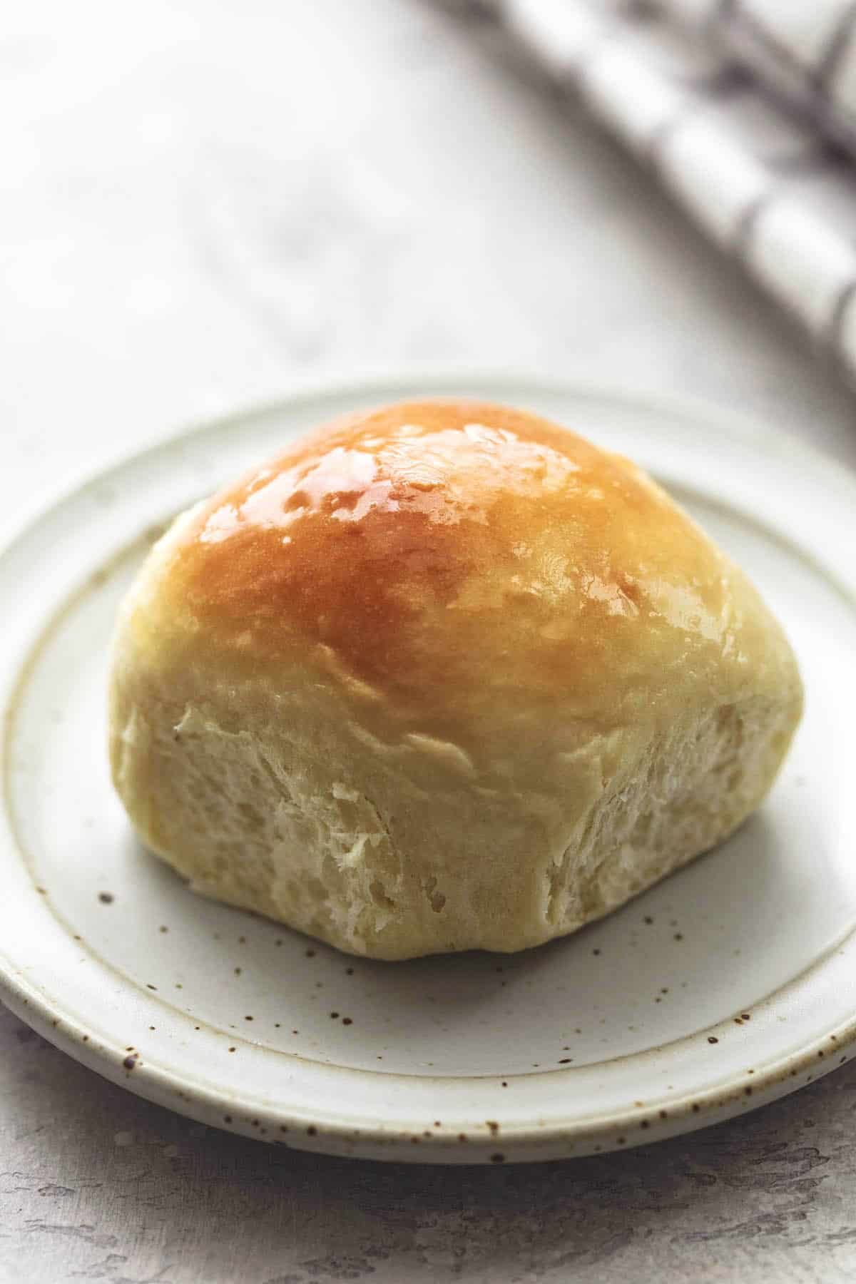 close up of a buttermilk dinner roll on a plate.