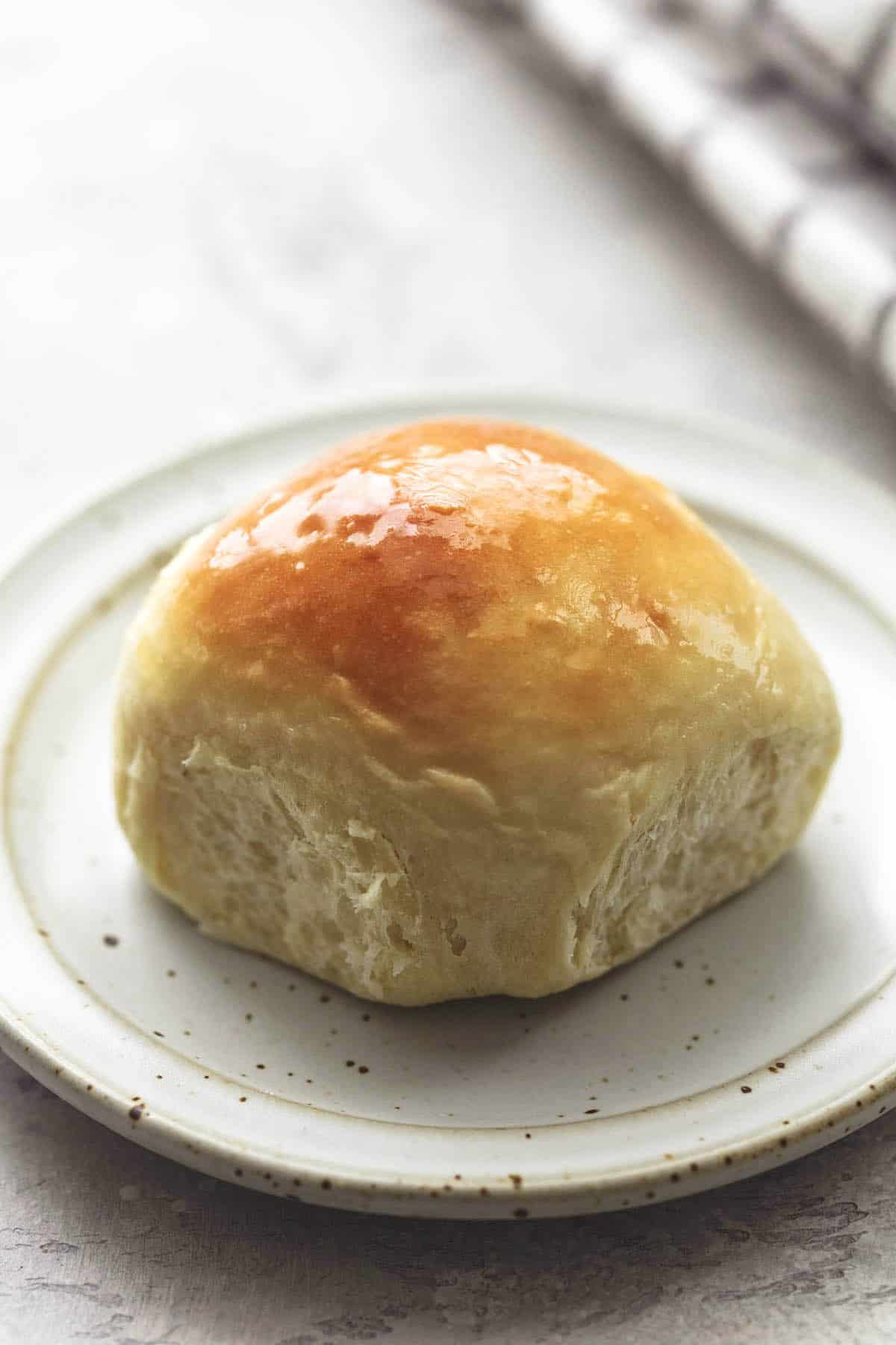 up close single baked dinner roll on a plate