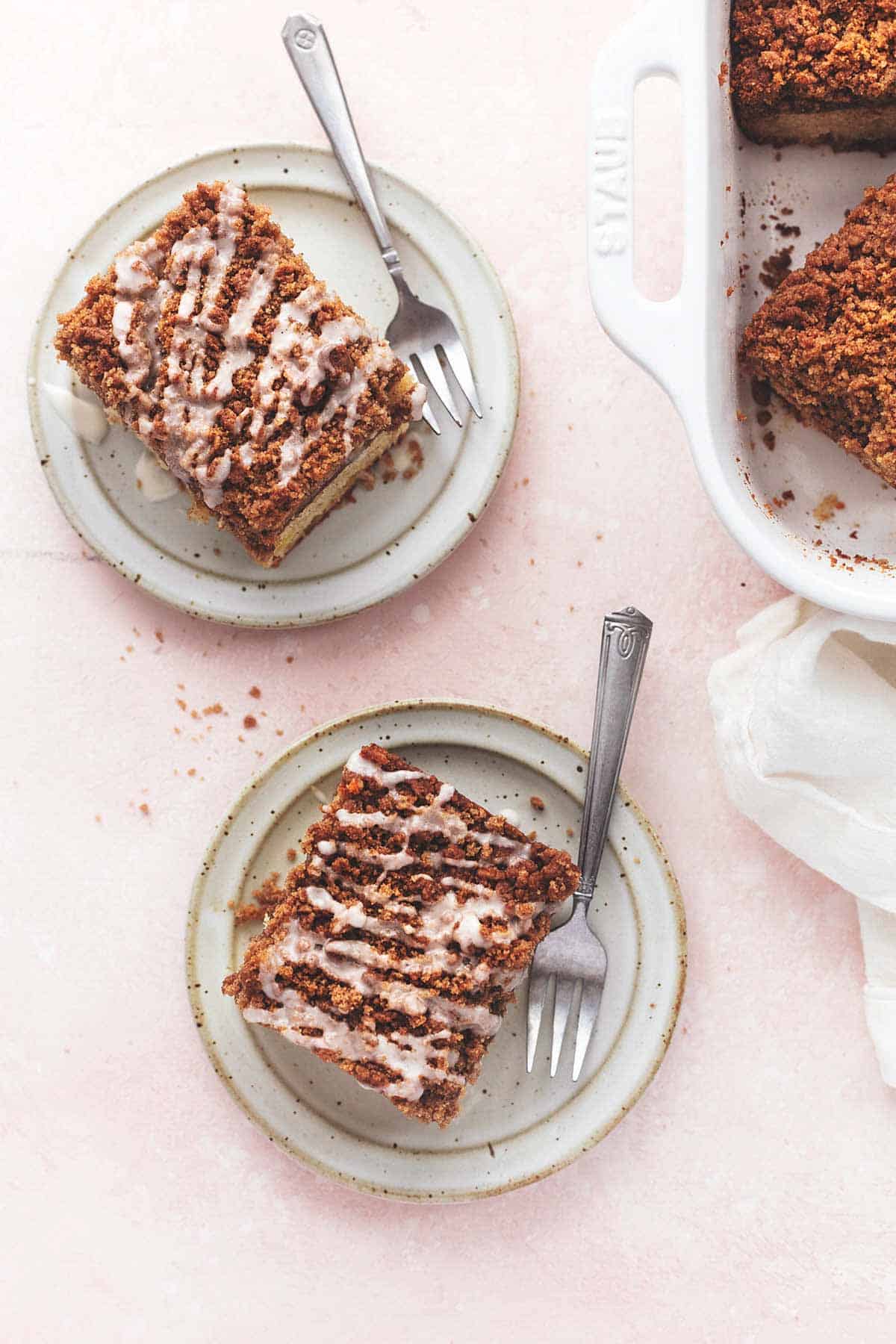 overhead view of two plates with pieces of cake and 1/4 of a baking dish with more cake