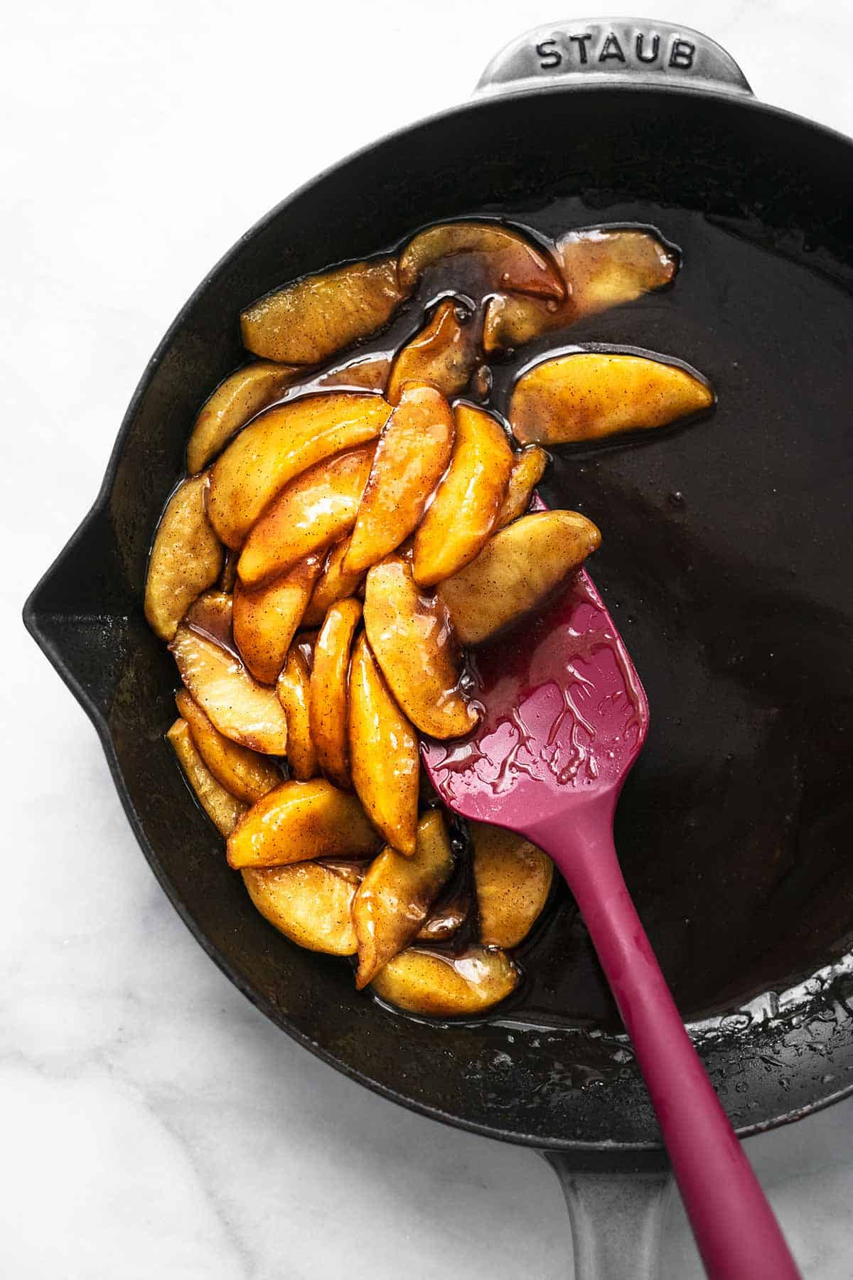 top view of apple compote in a skillet with a rubber spatula.