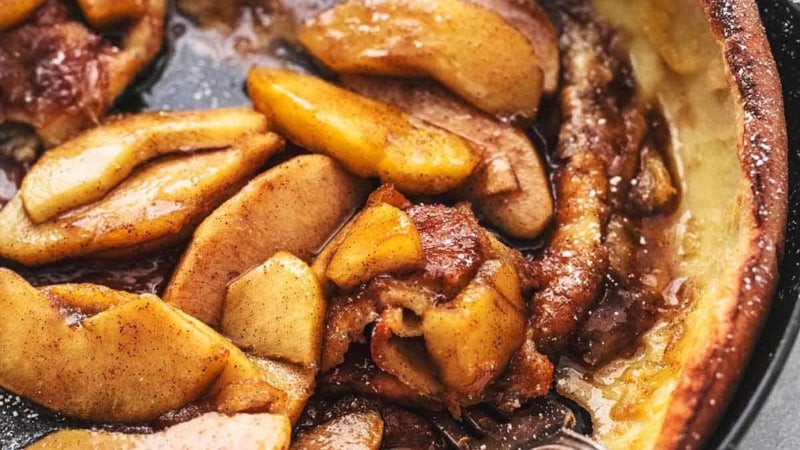 3/4 of a skillet with apple dutch baby and fork digging into pancake