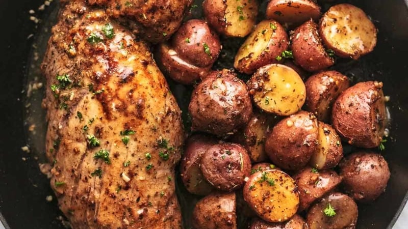 overhead view of pork tenderloin and baby potatoes cooked in a skillet