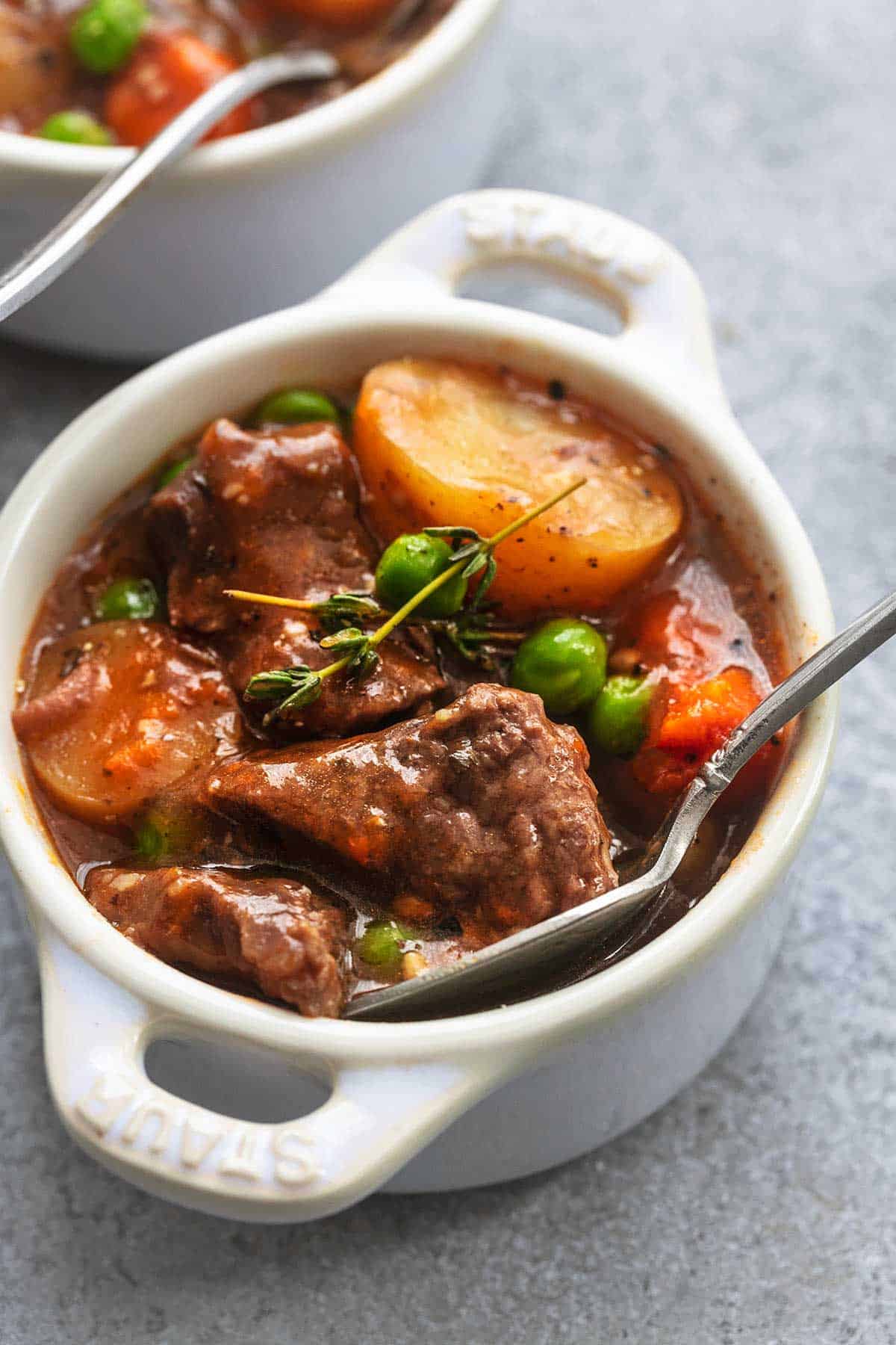 up close view of beef, potatoes, peas, carrots, in thick brown sauce with spoon in mini coquette