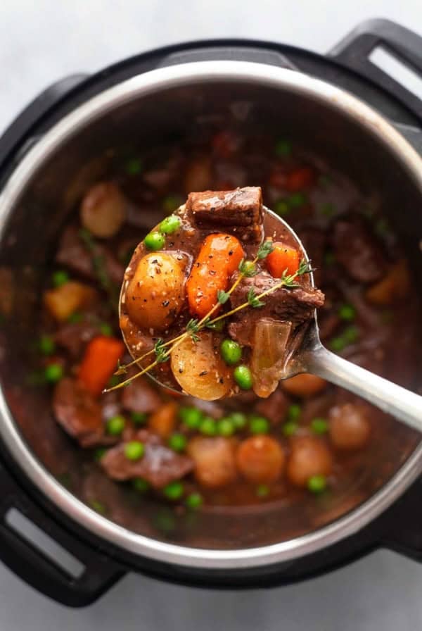overhead view of ladle filled with beef stew above pot filled with more beef stew