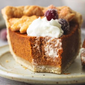 head-on view of bite missing from piece of pie with brown filling and sugared cranberries
