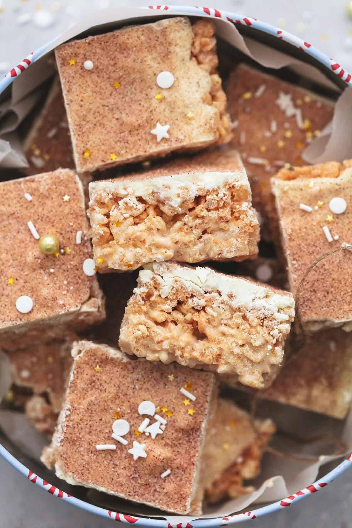 close up top view of churro Krispie bars with sprinkles in a holiday tin.