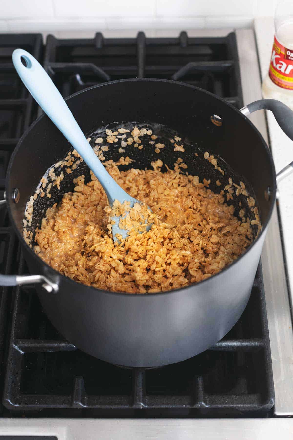a rubber spatula and rice cereal with marshmallows in a pot on a cooktop.