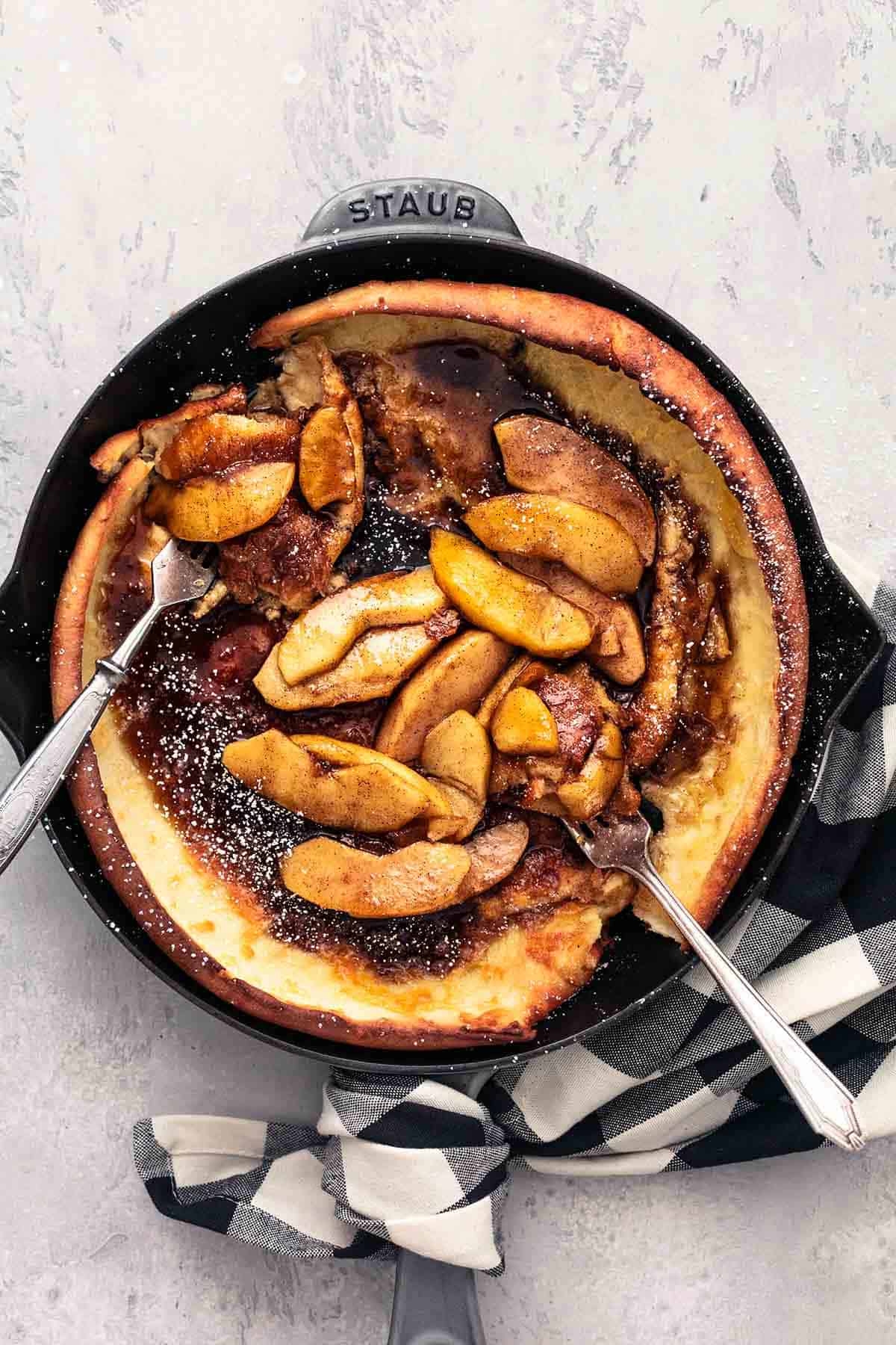 top view of apple dutch baby in a skillet with forks.