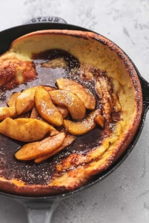 cast iron skillet with pancake and sliced apples and dark sauce