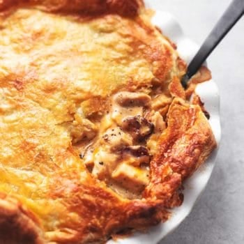 chicken and mushroom pie with black serving spoon in white pie dish