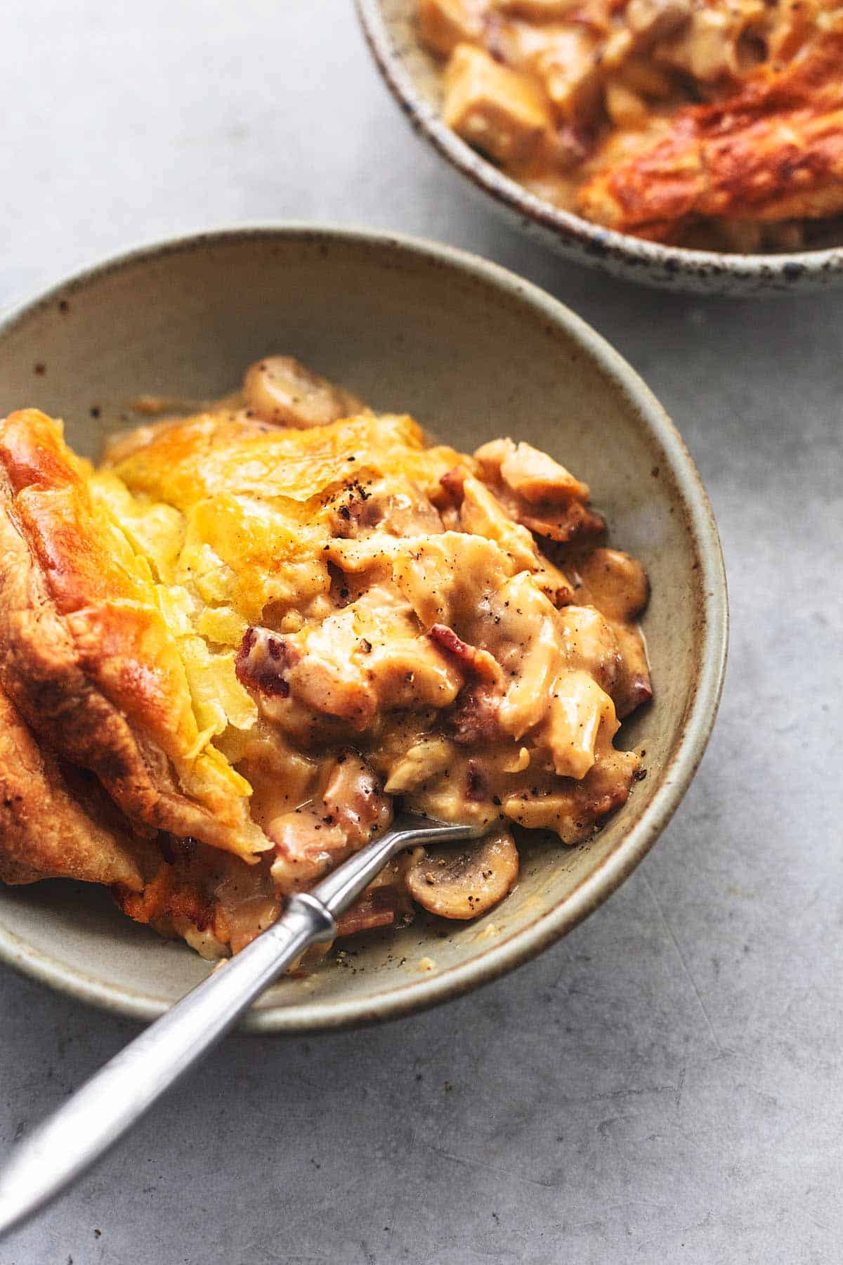 close up of chicken and mushroom pie with a fork in a bowl.