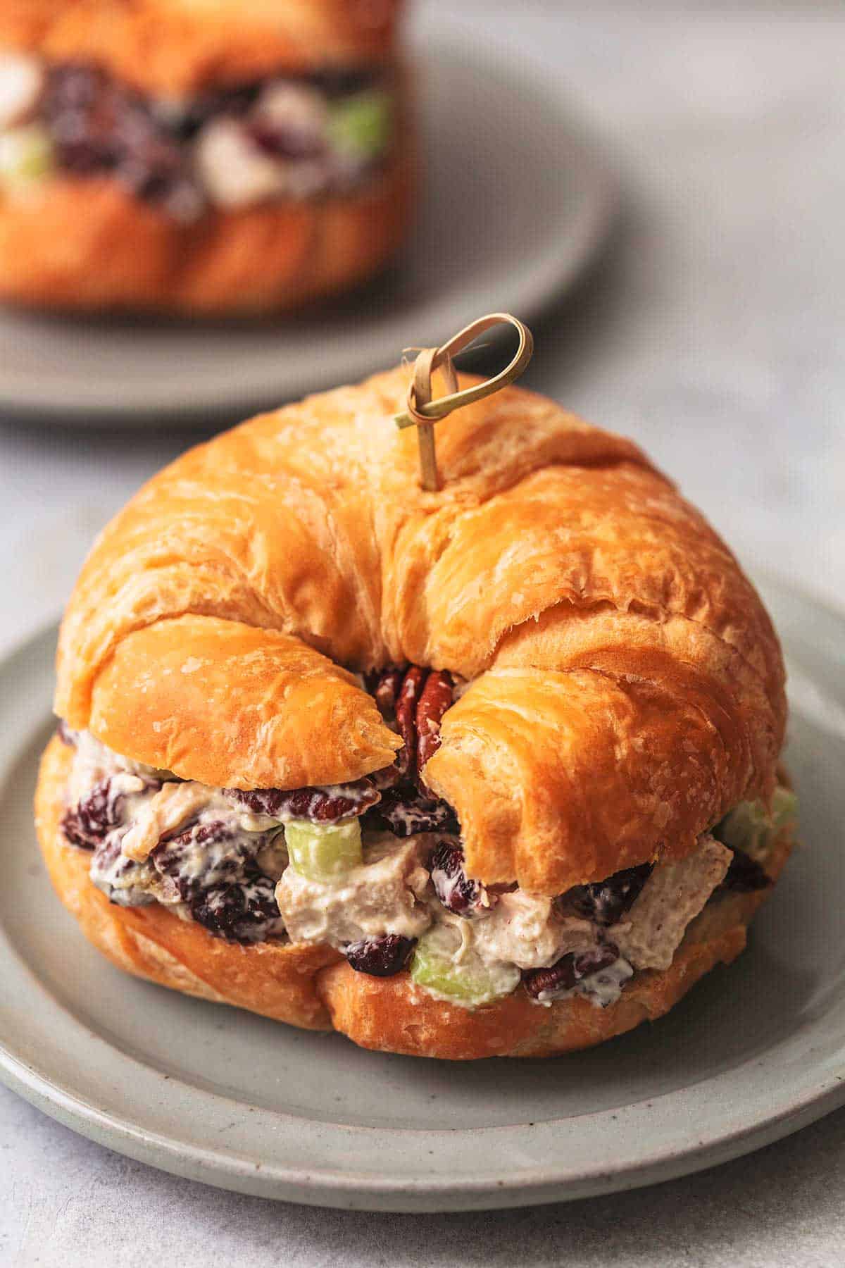 croissant with turkey salad on gray plate with second sandwich in background