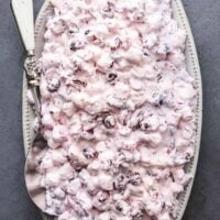 overhead view of cranberry salad on serving platter with serving spoon on dark table