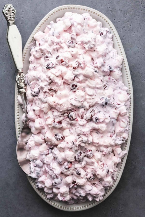 overhead view of cranberry salad on serving platter with serving spoon on dark table