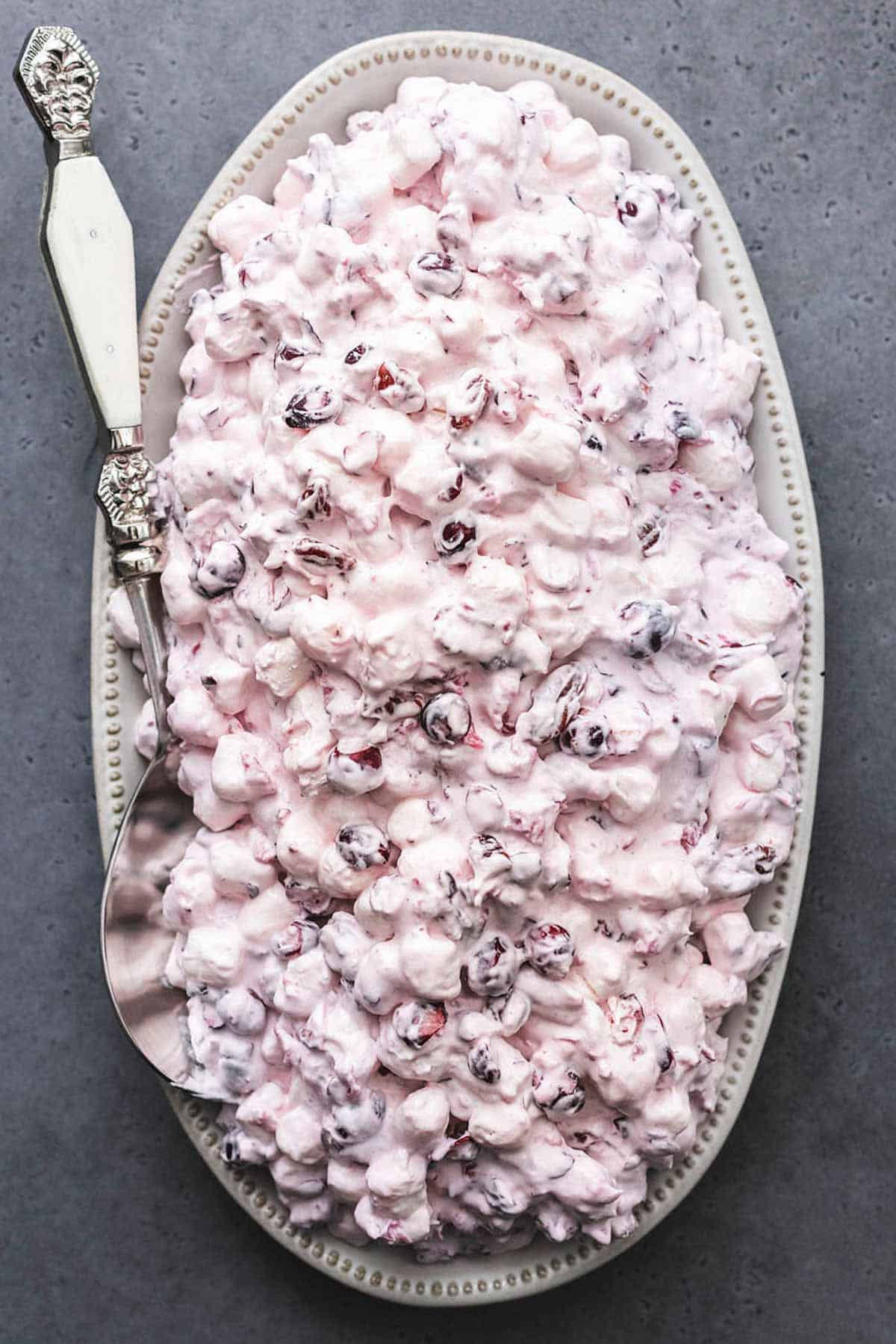 top view of cranberry salad on a serving platter with a serving spoon.