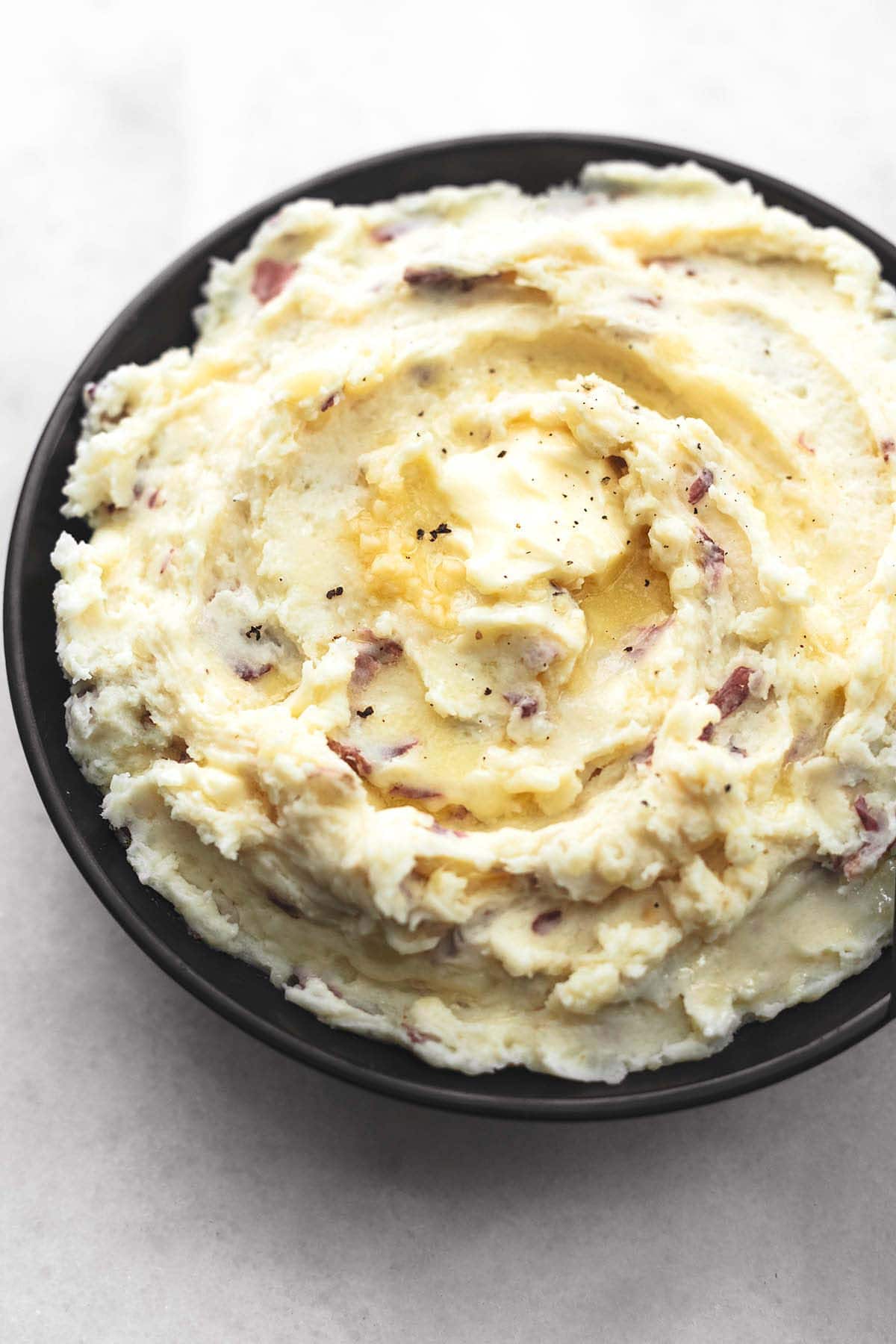 mashed potatoes with butter melting in a black bowl