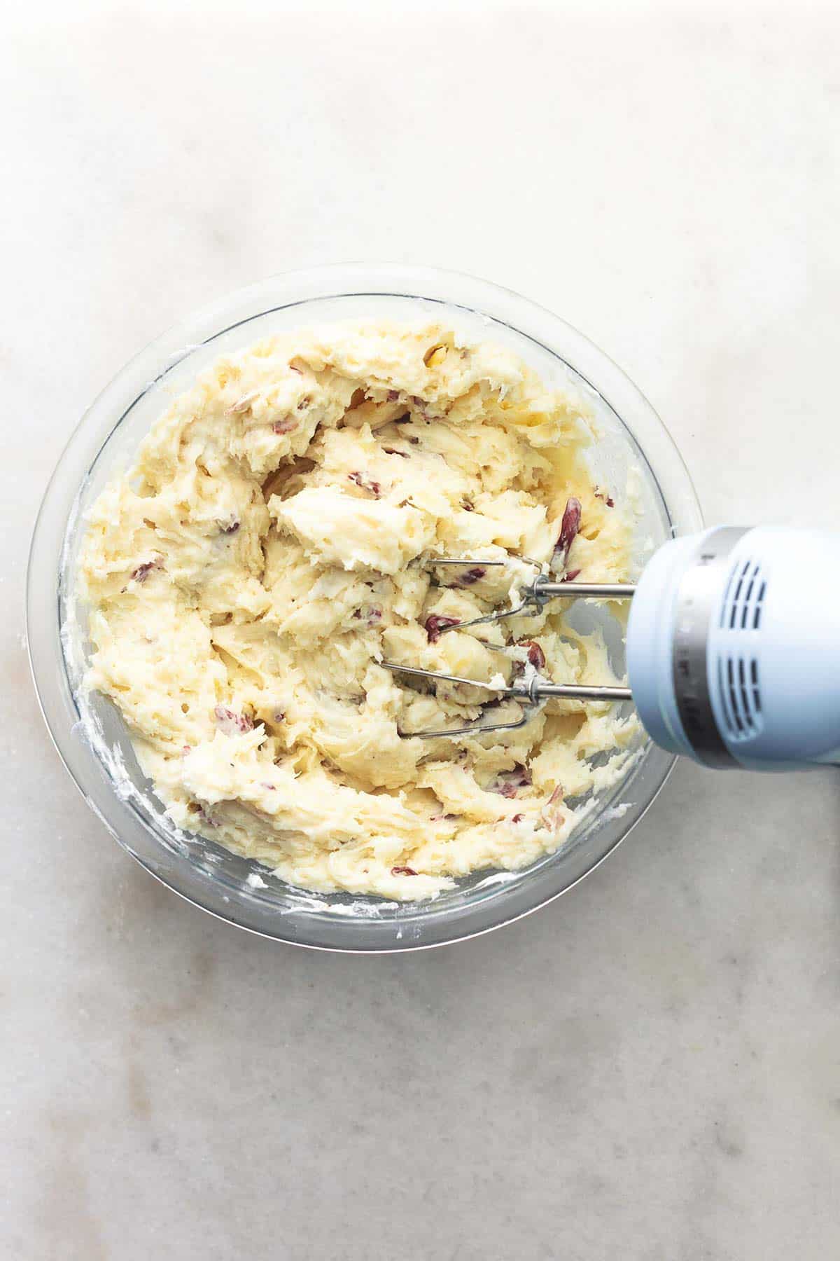top view of electric mixer beaters in a bowl of whipped potatoes.