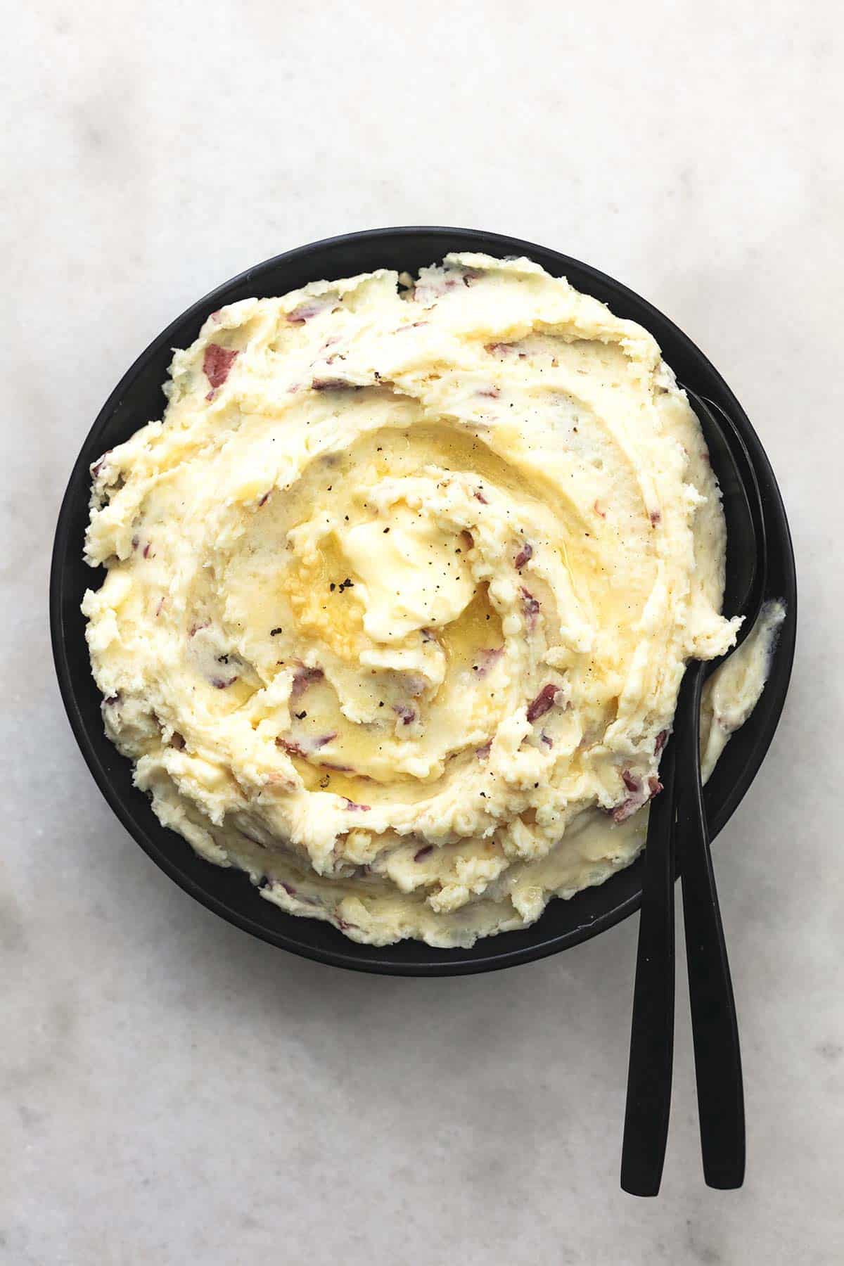 top view of garlic mashed potatoes with serving spoons in a bowl.