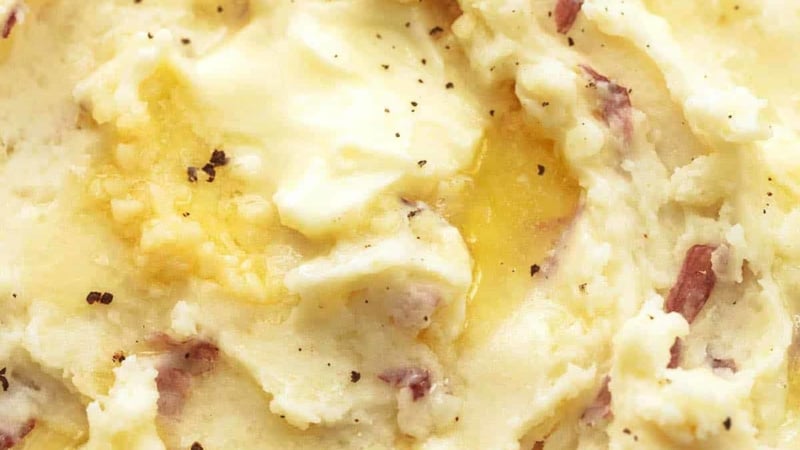 close up butter melting in mashed potatoes with some red skins and garlic