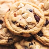 up close pile of cookies with white chocolate chips and cranberry pieces